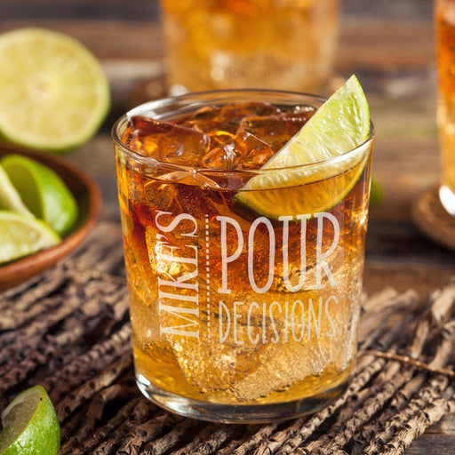 Personalized whiskey glass displayed with whiskey, ice, and fresh lime on a rustic wooden surface. The “Mike’s Pour Decisions” engraving is clearly visible, showing how the finished custom rocks glass looks in a stylish home bar setting.