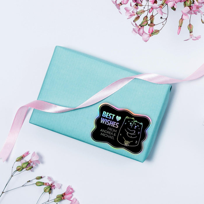 Small wrapped gift box decorated with a rainbow foil Bear Couple wedding gift tag tied with twine. Styled with soft pastel colors and floral accents for a wedding or bridal shower presentation.
