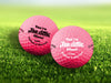 Two golf balls with Tee-Riffic design printed on them, placed on a grassy field.