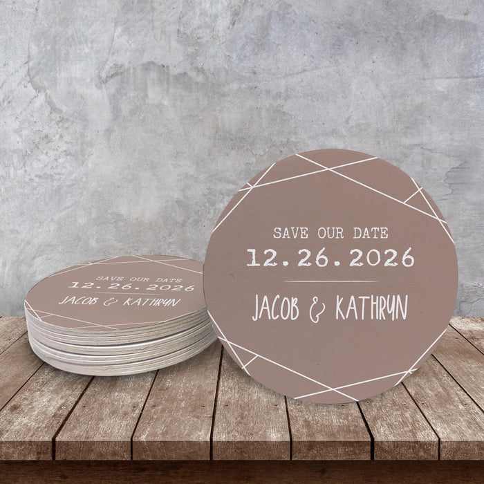Personalized Save the Date coasters displayed on a rustic wood surface. Features a modern geometric design with custom names and wedding date.