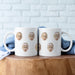 Two personalized grandkids face mugs displayed together on a wooden table.