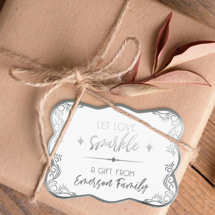 Personalized “Let Love Sparkle” wedding gift tag attached to kraft paper wrapping with natural twine. The metallic silver foil and decorative border create an elegant keepsake-style look.