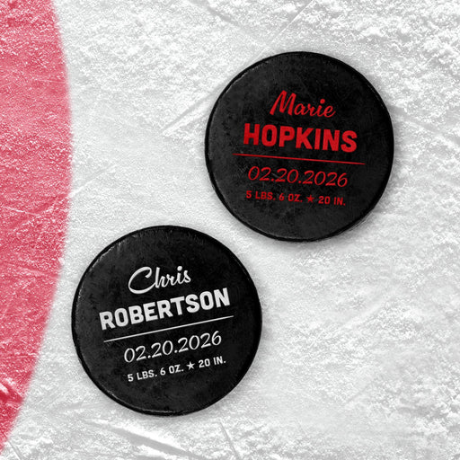 Two personalized hockey pucks with UV printed baby birth announcement details shown in red and white on an icy background.