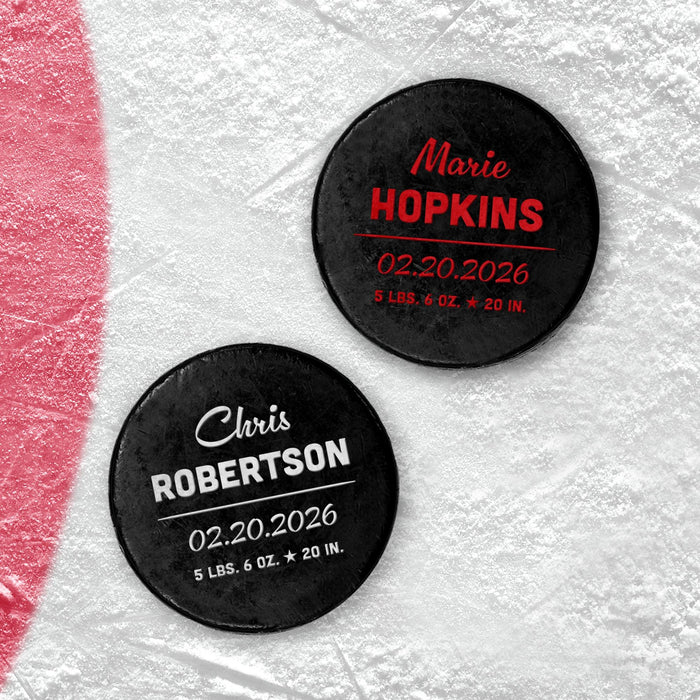 Two personalized hockey pucks with UV printed baby birth announcement details shown in red and white on an icy background.