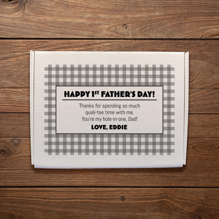A white gift box for a dozen of golf balls is shown with a custom message printed on it, placed on a wooden surface.