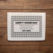 A white gift box for a dozen of golf balls is shown with a custom message printed on it, placed on a wooden surface.