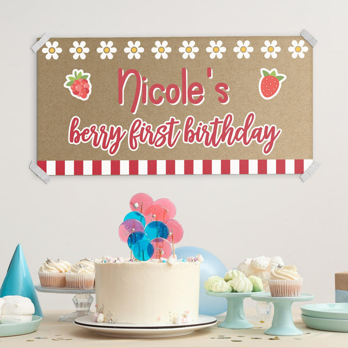 Personalized berry first birthday banner styled above a birthday cake table setup for a fun strawberry themed first birthday party.
