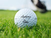 Titleist golf ball is shown sitting on grass. Ball features custom printed Newlyweds&#39; Names design.