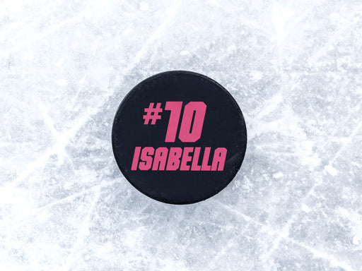 single hockey puck on ice rink with name and number design printed in pink that says Isabella number 10