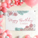Floral banner displayed as a party backdrop with pink balloon decorations and custom text.