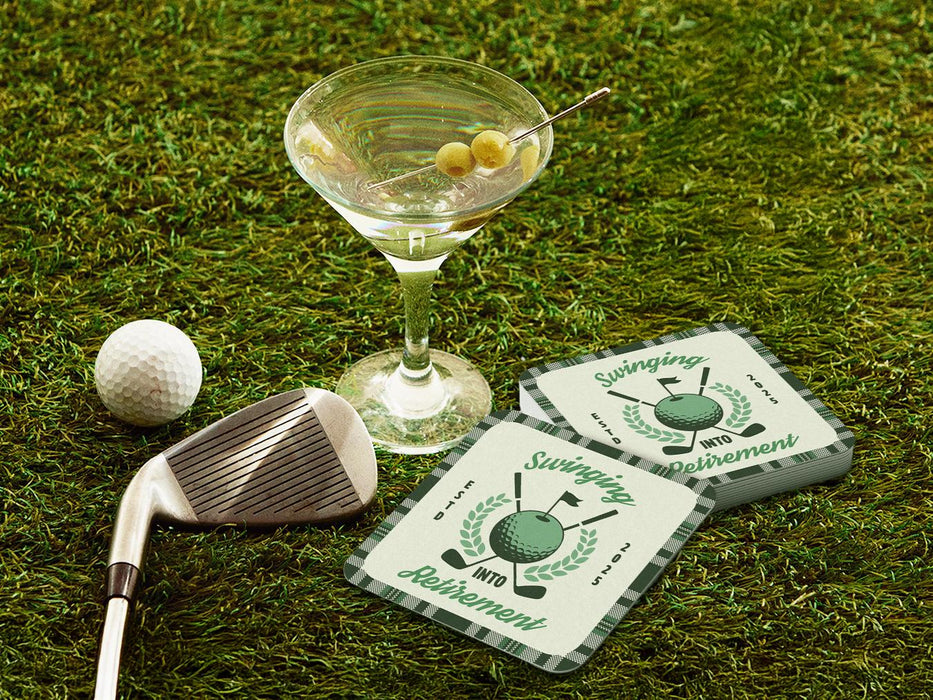 Custom square pulpboard coasters are shown sitting on a grassy, green golf course next to a martini glass, white golf ball, and golf club. The coaster features design with illustrated golf ball, club, and flag on top with wreath surrounding it, argyle background pattern, and custom text.