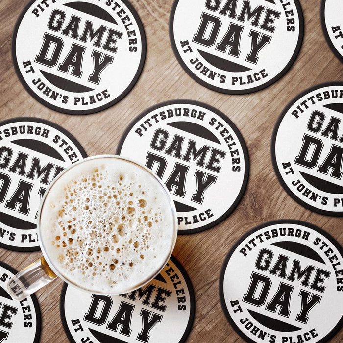 Black and white Game Day coasters arranged around a drink, showing the bold varsity-style personalized design.