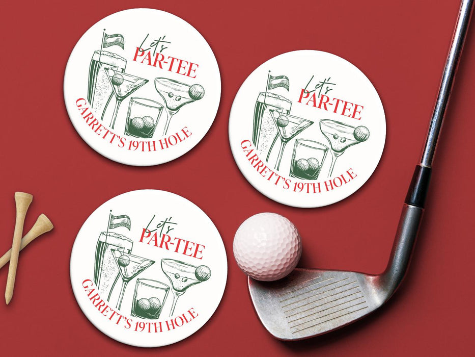 Custom square pulpboard coasters are shown sitting on a red surface. Golf tees, a golf ball, and a golf club sit beside them. The custom coasters feature design printed with green sketched cocktails with golf balls and flags within the drinks, and red and green text.