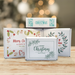 Personalized Christmas golf ball gift boxes displayed in a festive holiday setting, featuring four printed Christmas designs with custom messages.