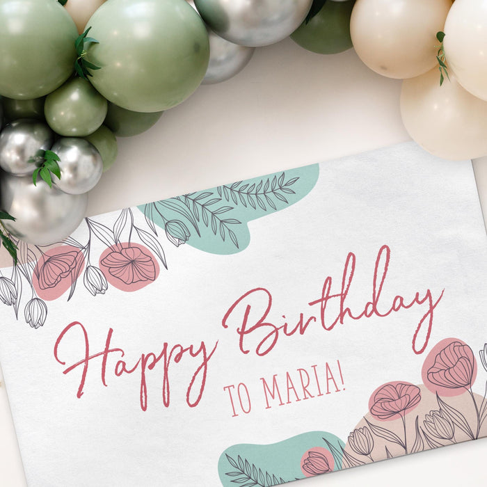 Floral celebration banner displayed beneath a balloon garland featuring a custom message and personalized text.