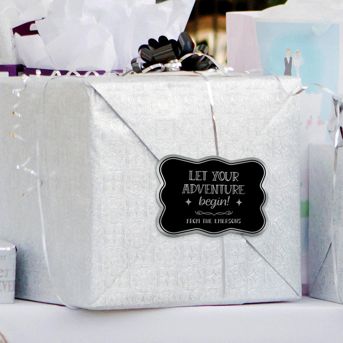 Silver gift bag decorated with a personalized “Let Your Adventure Begin” foil wedding gift tag in metallic silver and black. Styled as elegant packaging for weddings, bridal showers, and engagement gifts.