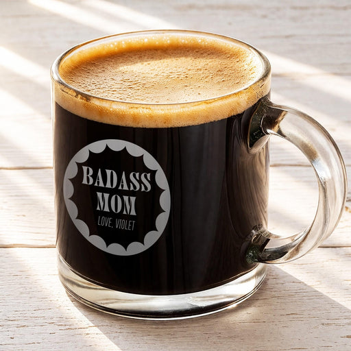 A mug of dark coffee with a foam top, sitting on a wooden surface.