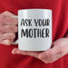 A person in a red sweater holding the “Ask Your Mother” mug with both hands. The cozy lifestyle setting adds warmth and playful gift appeal.