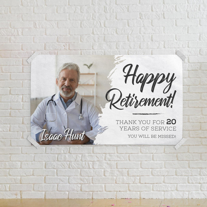 Happy Retirement banner displayed on a white brick wall. Personalized with a custom photo, retiree name, and years of service for a memorable retirement celebration.