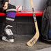 Lifestyle image of a hockey player in skates holding a personalized mini hockey stick with custom baby name design.