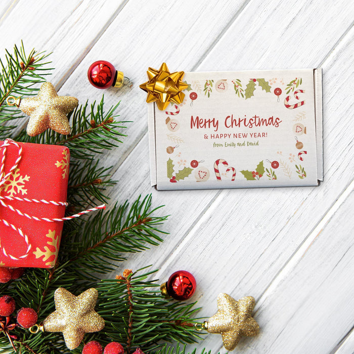 Personalized Christmas golf ball gift box displayed with evergreen branches, ornaments, wrapped gift, and star decorations, printed with a colorful Merry Christmas design.