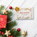 Personalized Christmas golf ball gift box displayed with evergreen branches, ornaments, wrapped gift, and star decorations, printed with a colorful Merry Christmas design.