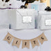Silver wedding gift bag decorated with a personalized “Let Love Sparkle” gift tag in metallic silver foil. Styled with wedding décor and hanging banner accents for a romantic presentation.