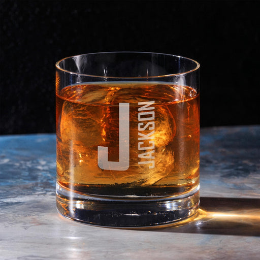 Clean hero-style image of the personalized whiskey glass on a marble surface, featuring the large initial and vertical name design. The engraving appears crisp and professionally finished.