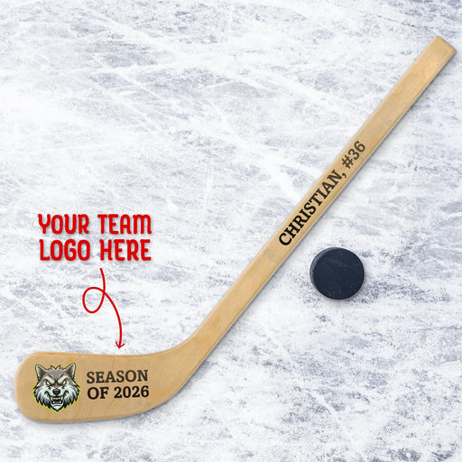 Personalized mini wooden hockey stick featuring custom team logo printed on the blade with space for team name and season text, shown on an ice background with a hockey puck.