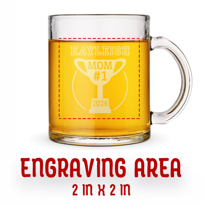 A glass mug with an engraved design on it. The mug is filled with tea, and there is text under the mug that reads "Engraving Area is 2 in x 2 in”