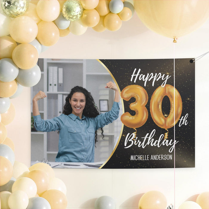 Black and gold birthday banner displayed as a party backdrop with gold and white balloon decorations.