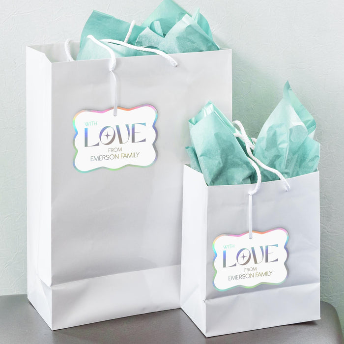 White gift bags with tissue paper featuring personalized “With Love” foil wedding gift tags in holographic rainbow foil. Styled as elegant wedding welcome bag and favor packaging ideas.