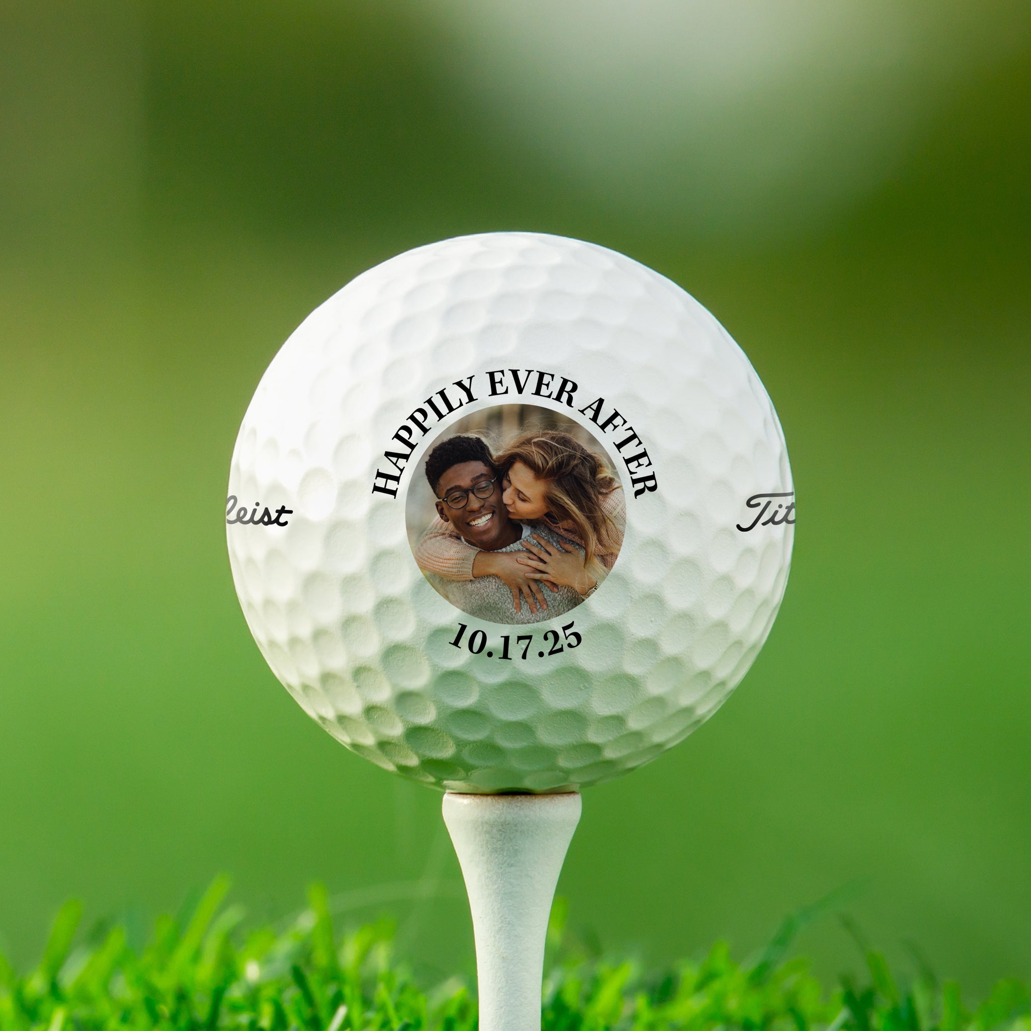 A white golf ball with a personalized message and a photo of a couple on it, placed on a grassy field.