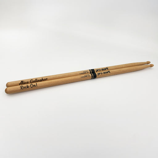 A pair of wooden drumsticks with the name "Alice Gallagher" and the words "Rock On!" engraved on them.