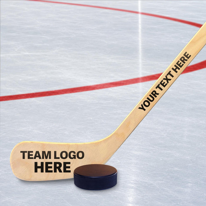Personalized hockey stick displayed on an ice rink with “team logo here” placeholder on the blade and custom text along the handle.