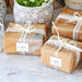 Small wrapped gift boxes tied with ribbon and decorated using personalized “With Love” foil gift tags. Elegant packaging idea for wedding favors and gifts.