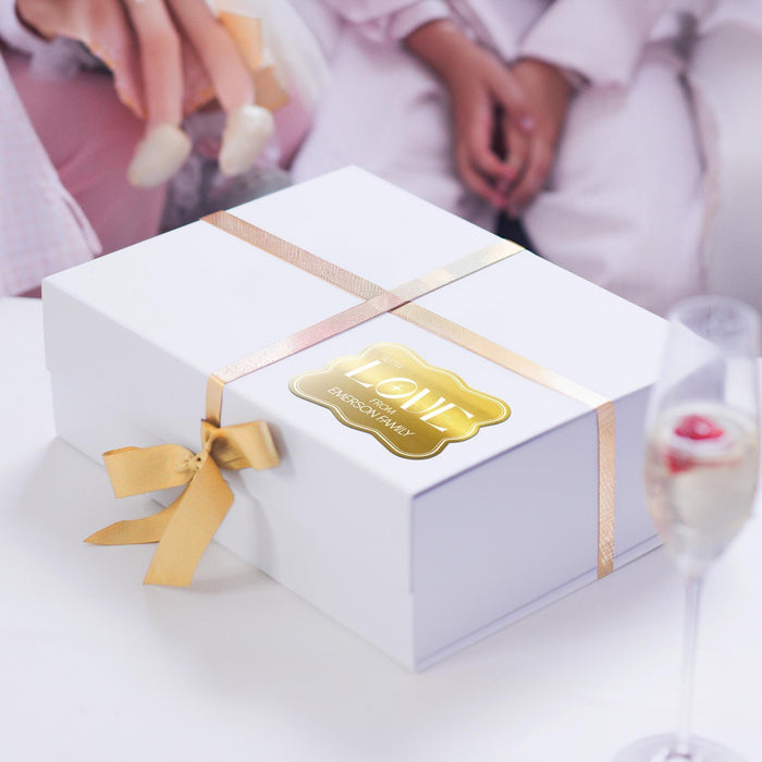 White gift box wrapped with satin ribbon and decorated using a gold foil “With Love” wedding gift tag. A premium wedding gift presentation idea for bridal showers and receptions.