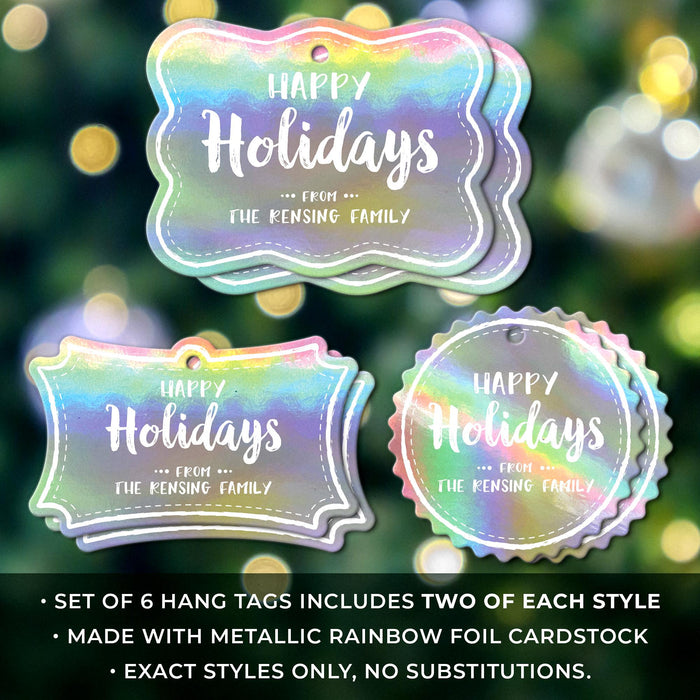 Set of 6 personalized Happy Holidays hang tags in three shapes displayed against a blurred Christmas tree with warm holiday lights.