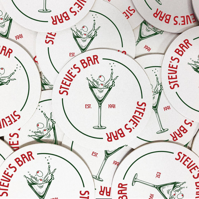 Several personalized dirty martini coasters arranged together, each featuring the custom bar name, martini glass with olives, and established year.
