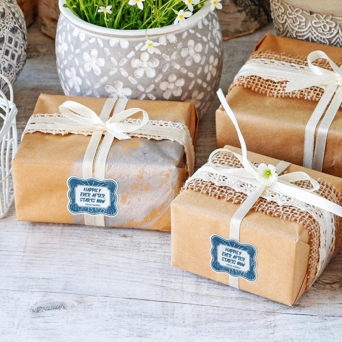 Wrapped kraft paper gifts decorated with custom “Happily Ever After Starts Now” gift tags. The personalized tags are tied with white string and styled for wedding favors or thank you gifts.