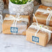 Wrapped kraft paper gifts decorated with custom “Happily Ever After Starts Now” gift tags. The personalized tags are tied with white string and styled for wedding favors or thank you gifts.
