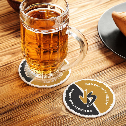 Custom rivalry coaster under a beer mug with another personalized football coaster displayed beside it on a wooden table.
