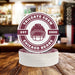 Stack of personalized Tailgate Crew football coasters featuring a helmet design, custom team name, and established year on a bar counter.