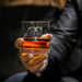 Close-up lifestyle photo of a personalized whiskey glass held in hand, featuring a large “T” initial with “Turner” engraved across the center. The glass is filled with whiskey and ice, creating a premium gift presentation.