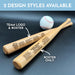 Two personalized mini baseball bats with 2 different design styles engraved on them, placed on a black surface next to a baseball. The two design styles shown are Team Logo & Roster and Roster Only.