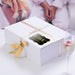 White gift box wrapped with satin ribbon and decorated using a personalized “With Love” gold foil wedding gift tag. A premium wedding gift presentation idea for bridal showers and receptions.