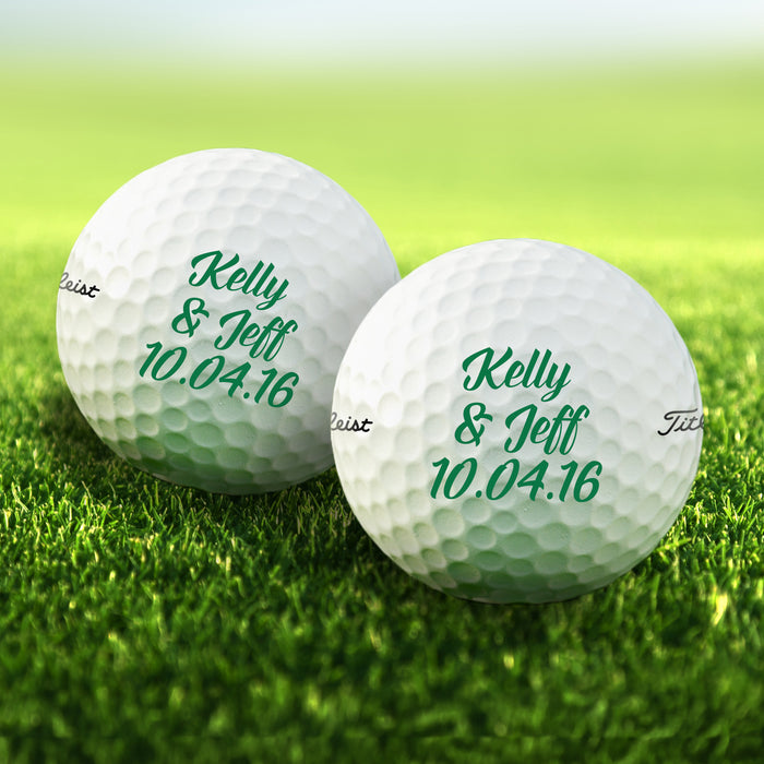 Two personalized golf balls with names and dates printed on them, placed on a grassy field.