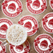Red custom tailgate coasters arranged around a beer, featuring a football helmet, team name, and established year.