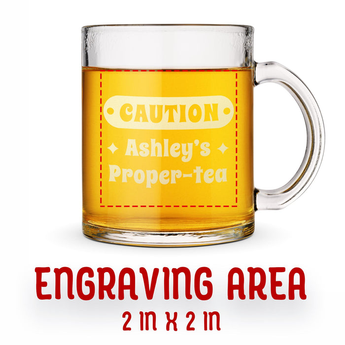 A glass mug with an engraved design on it. The mug is filled with tea, and there is text under the mug that reads "Engraving Area is 2 in x 2 in”