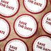 Personalized Save the Date coasters shown in a wedding favor arrangement. Modern wedding design customized with names and date.
